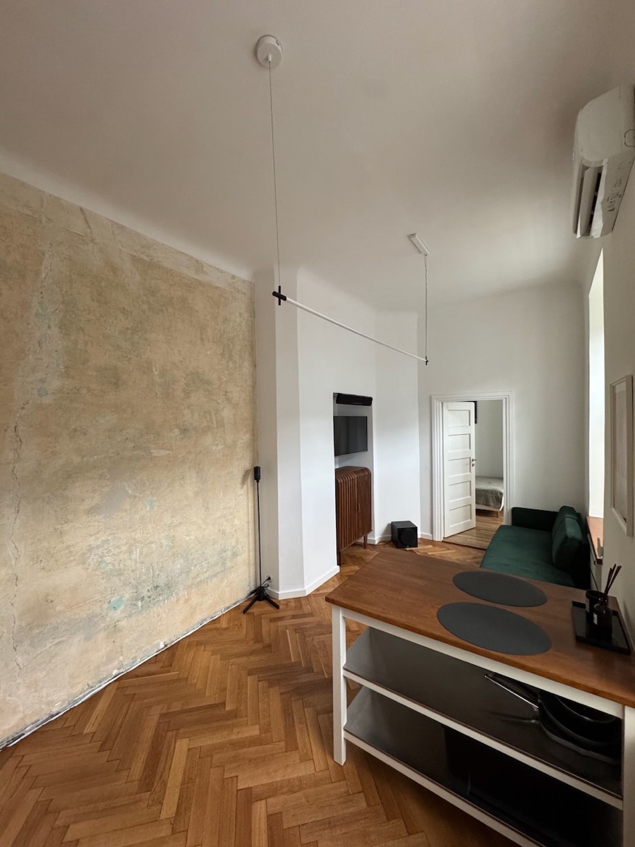 Full-height raw 1913 plaster wall in the living area, kitchen island in the foreground